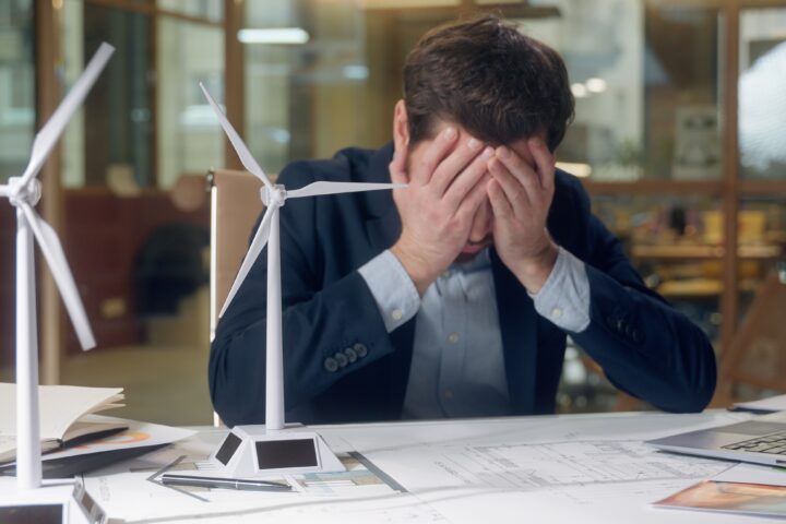 Stressed man at office desk holding his head in his hands, symbolising worry and the need to cast cares on God.