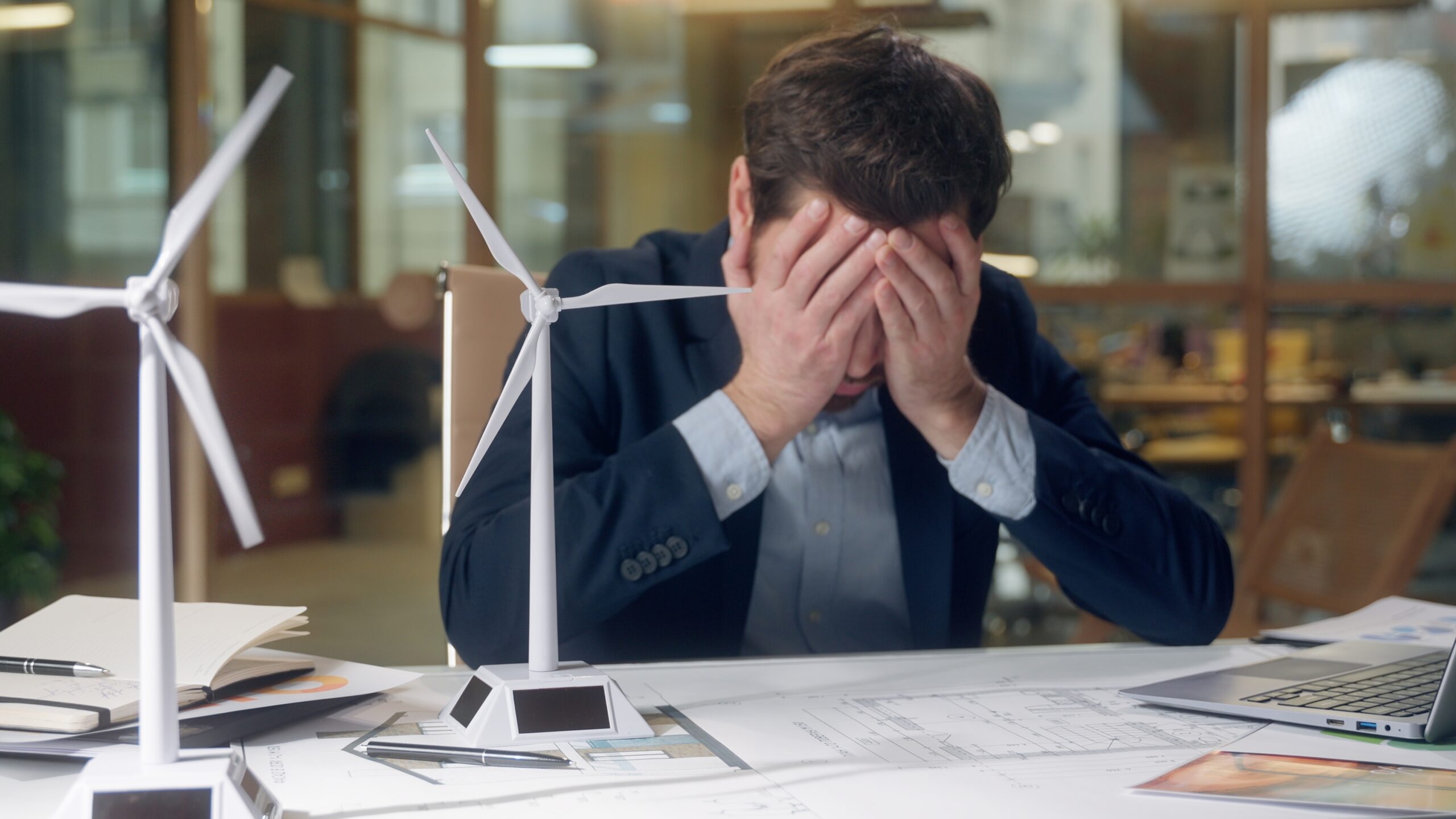 Stressed man at office desk holding his head in his hands, symbolising worry and the need to cast cares on God.